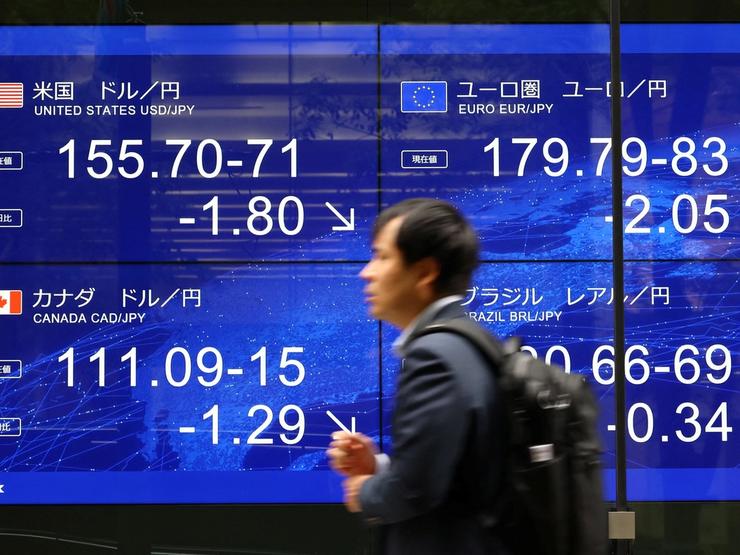 A man walks past an electronic screen displaying the current Japanese yen exchange rate against the U.S. dollar and other foreign currencies after Japan and the United States conducted coordinated yen-buying intervention, in Tokyo