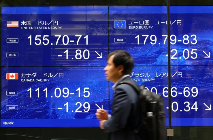A man walks past an electronic screen displaying the current Japanese yen exchange rate against the U.S. dollar and other foreign currencies after Japan and the United States conducted coordinated yen-buying intervention, in Tokyo