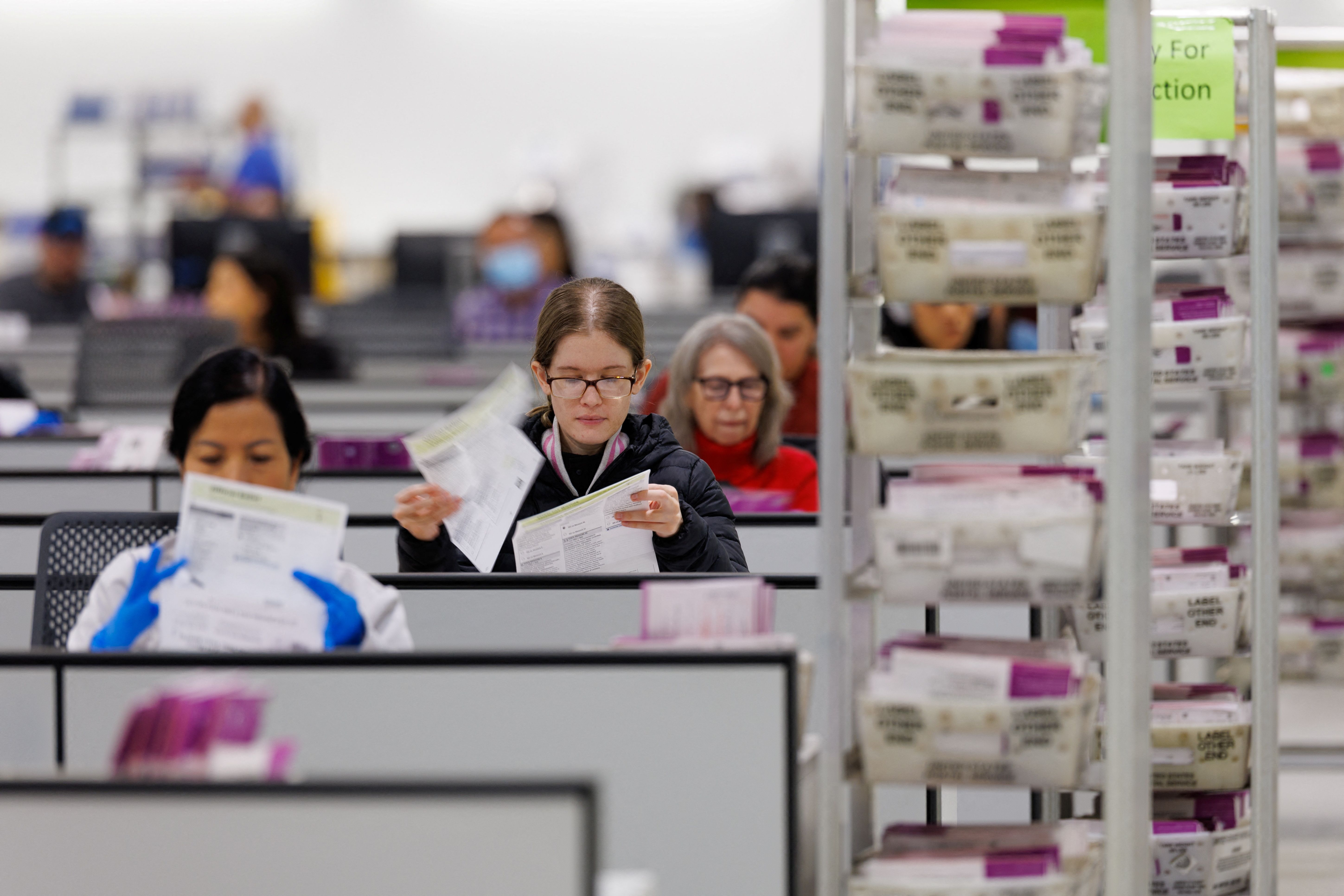 Election workers extract mail-in ballots 