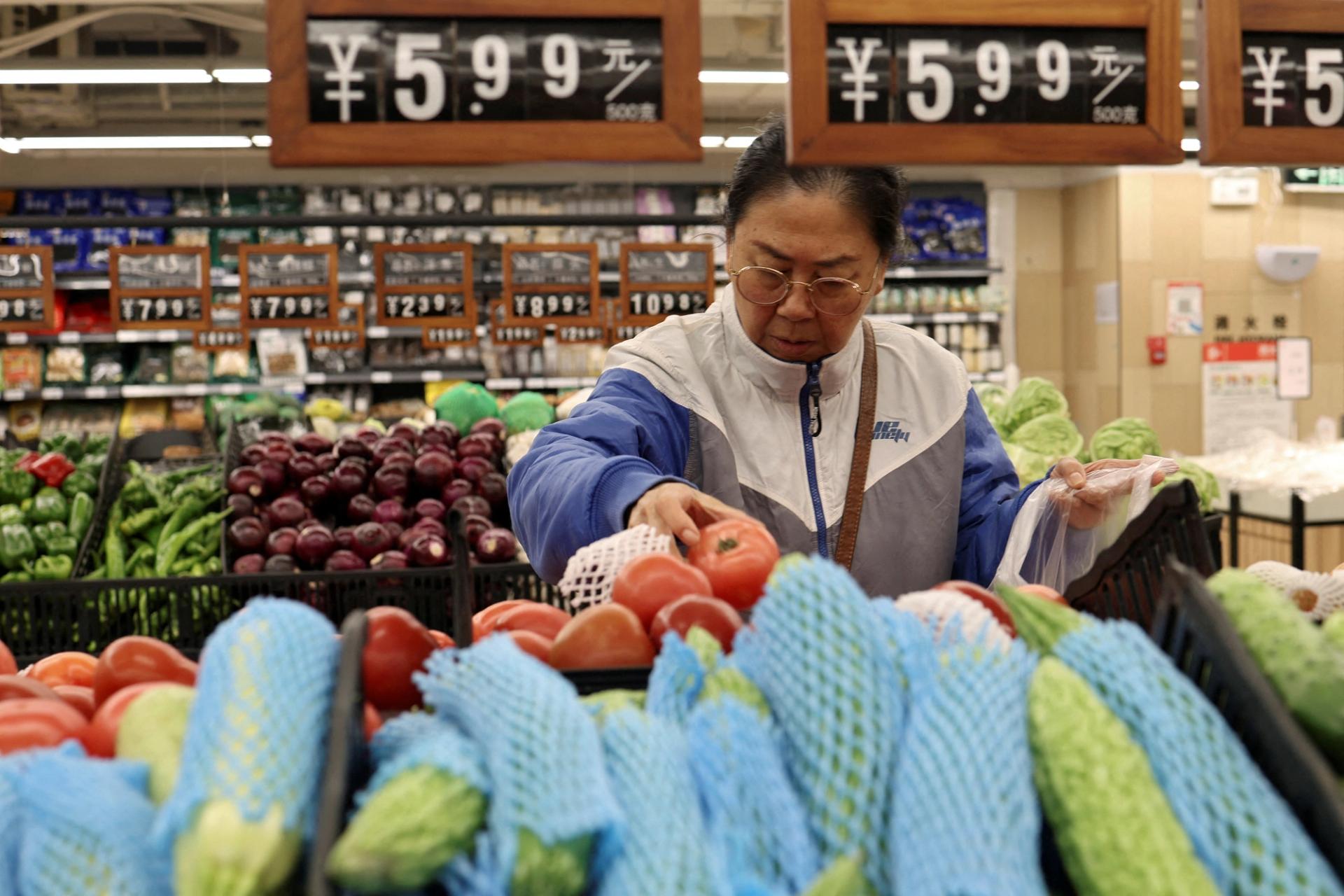 A customer shops for tomatoes at the vegetable section of a supermarket in Beijing