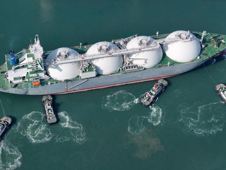 A drone view shows tugboats assisting a liquified natural gas (LNG) tanker to dock at a port in Yantai, Shandong province, China.