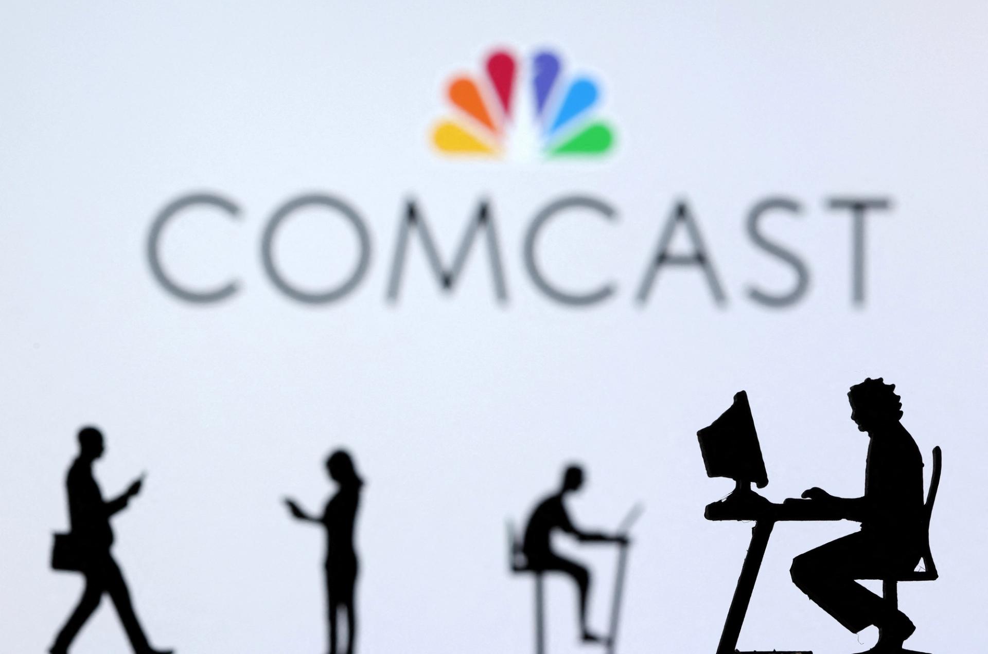 Small toy figures with laptops and smartphones are seen in front of a displayed Comcast logo