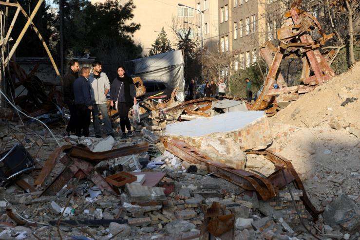 People look at a destroyed building following a strike, in Tehran.