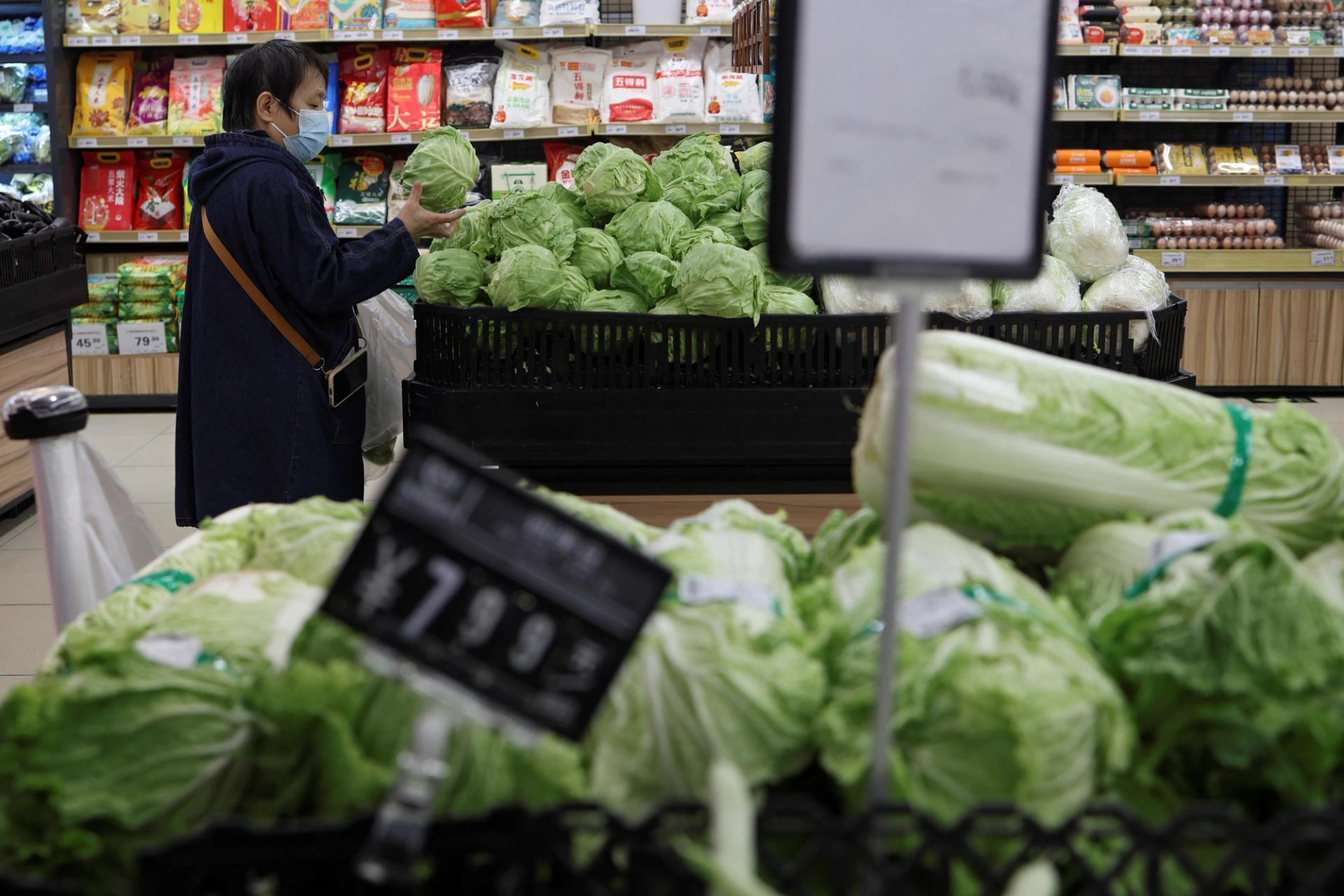 A customer shops for cabbages at the vegetable section of a supermarket in Beijing, China, 2024.