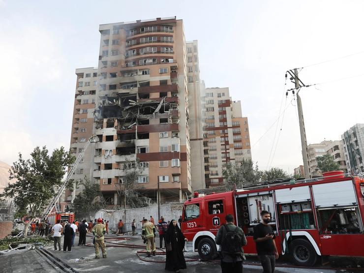 Firefighters work at the scene of a damaged building.