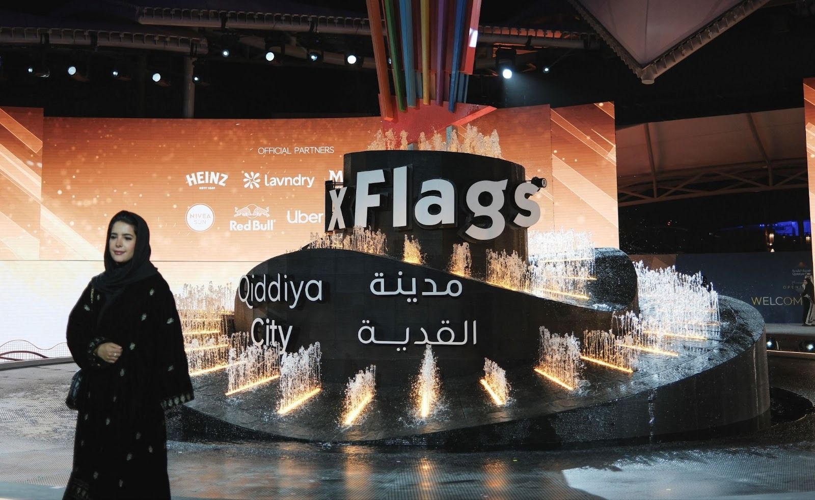 A visitor stands near the logo of Six Flags Qiddiya City amusement park during an inauguration ceremony at Qiddiya City.