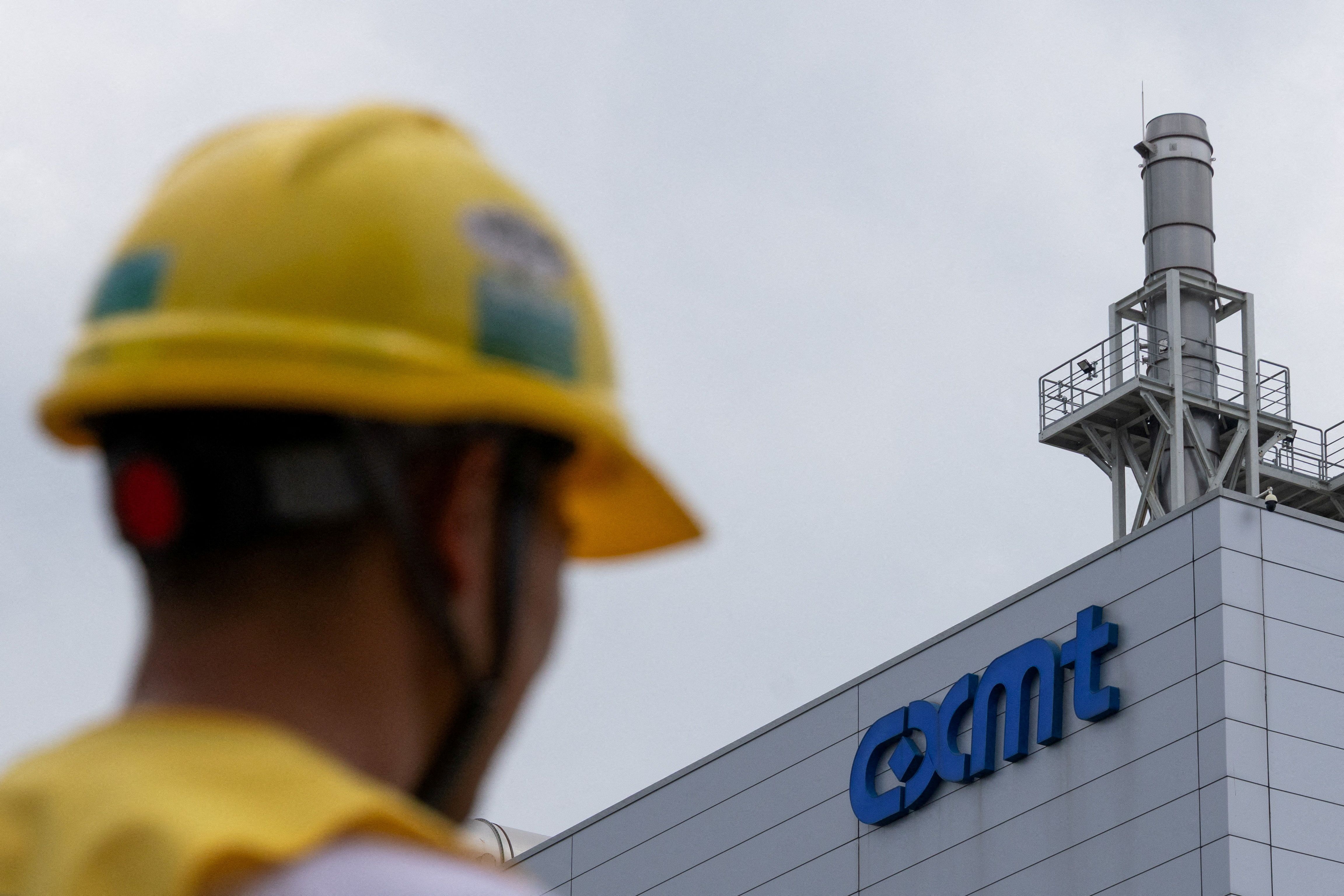  A man wearing a yellow protective helmet walks next to a production facility of China’s top memory chipmaker CXMT with company’s logo on the facade, in Beijing.