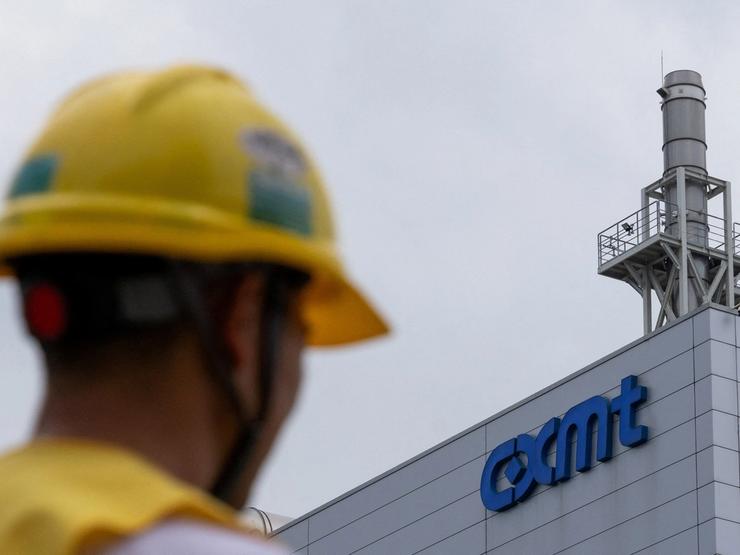 A man wearing a yellow protective helmet walks next to a production facility of China’s top memory chipmaker CXMT with company’s logo on the facade, in Beijing.