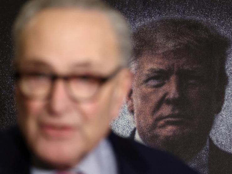 Chuck Schumer with Donald Trump in the background