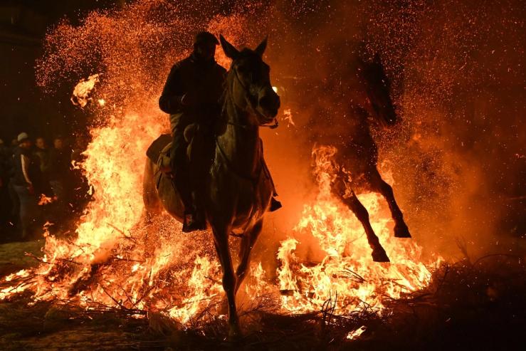 A horseman rides his horse through a bonfire during the ‘Las Luminarias’ festival in the village of San Bartolome de Pinares