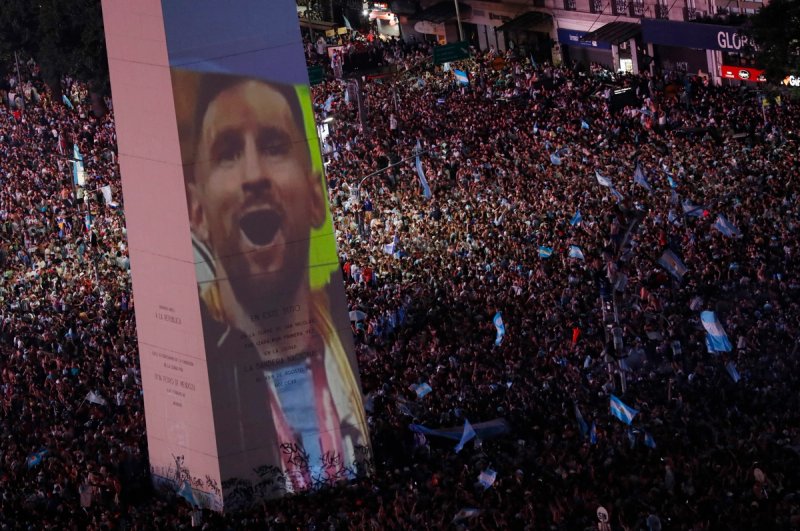 Fans celebrate winning the World Cup at the Obelisk with an image of Lionel Messi 