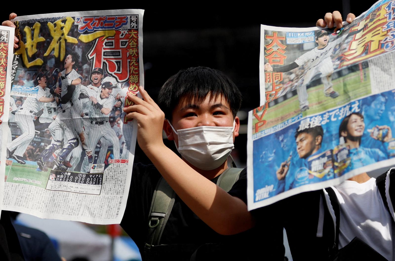 A person holds up a special edition newspaper, reporting Japan's victory at the World Baseball Classic final, in Tokyo, Japan, March 22, 2023. REUTERS/Kato Issei