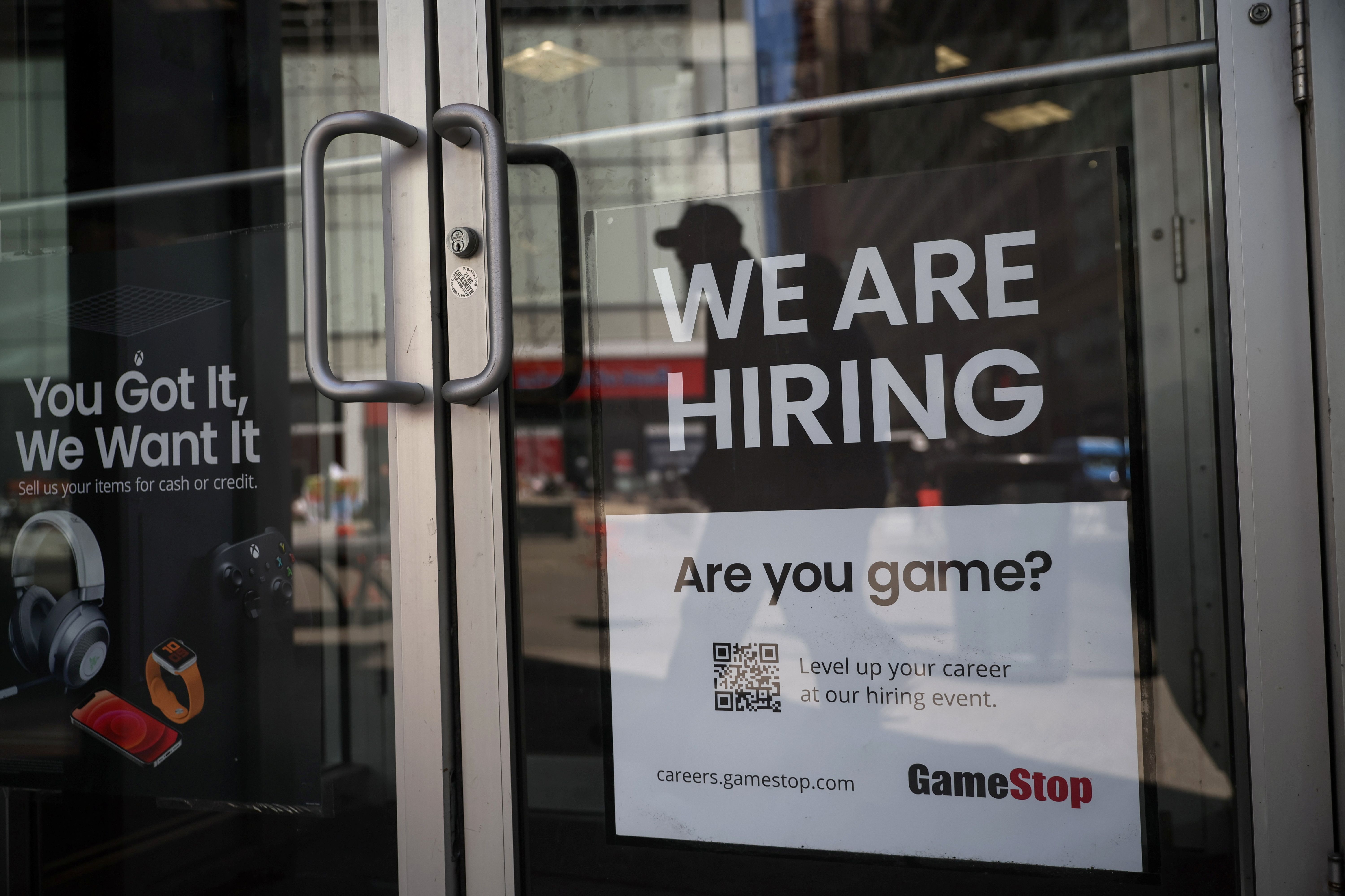 A sign for hire is posted on the door of a GameStop in New York City