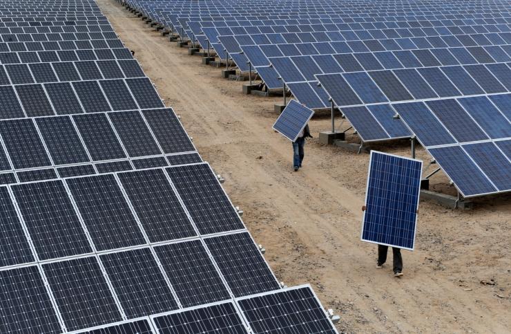 Employees carry solar panels at a solar power plant in Aksu, Xinjiang Uyghur Autonomous Region May 18, 2012.