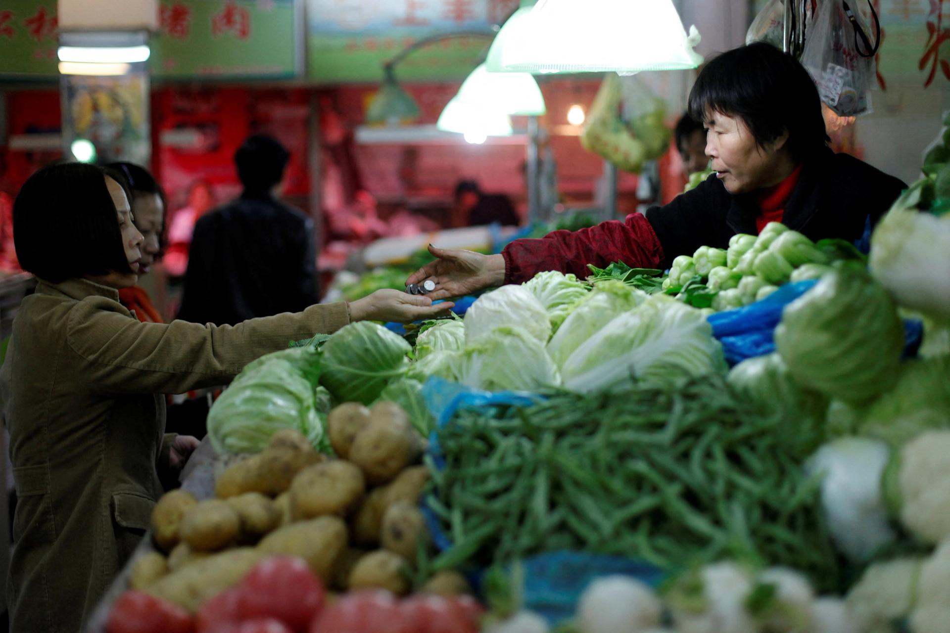 A customer receives her change after buying vegetables at a market in central Shanghai.