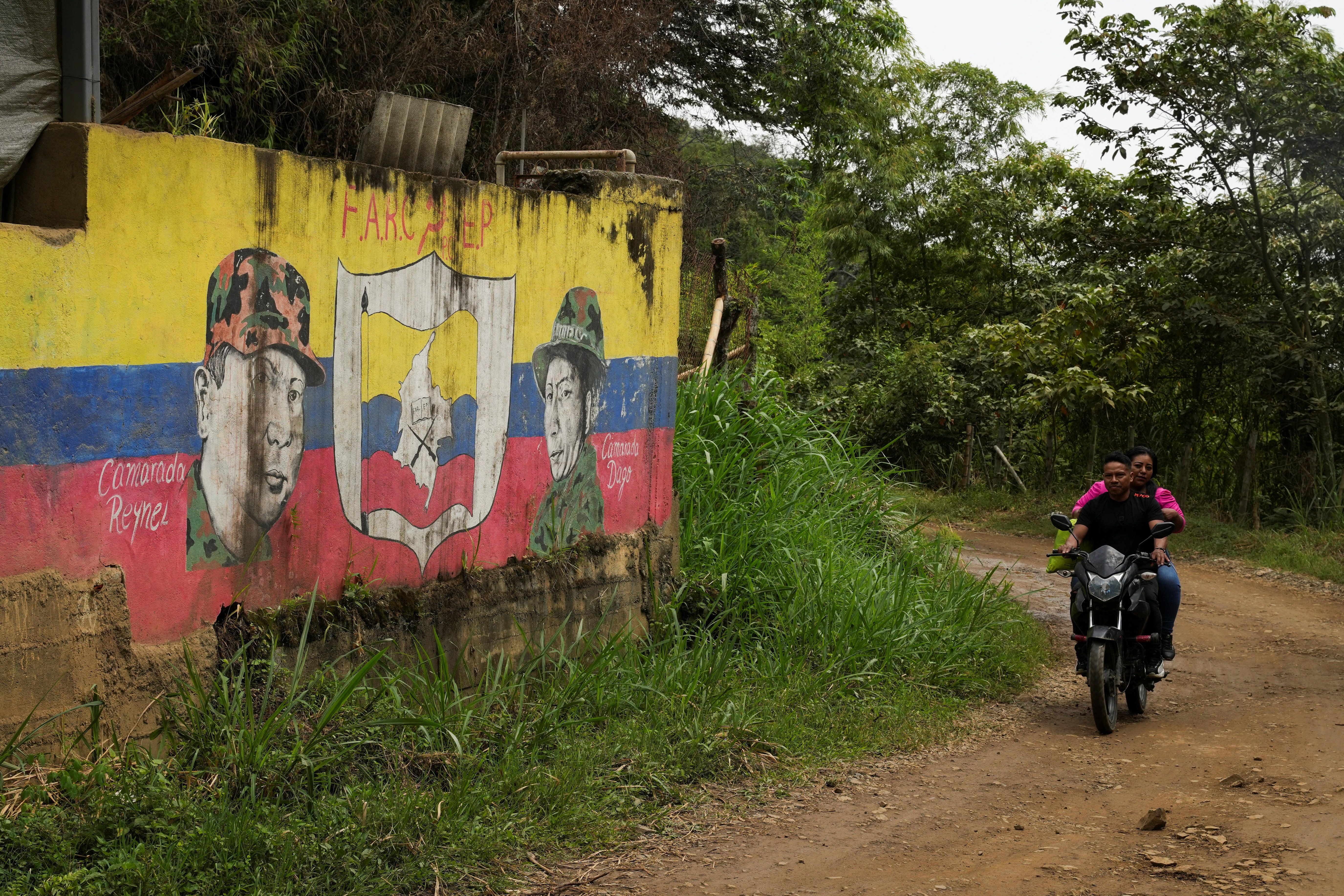 A motorcyclist drives past a colombia flag
