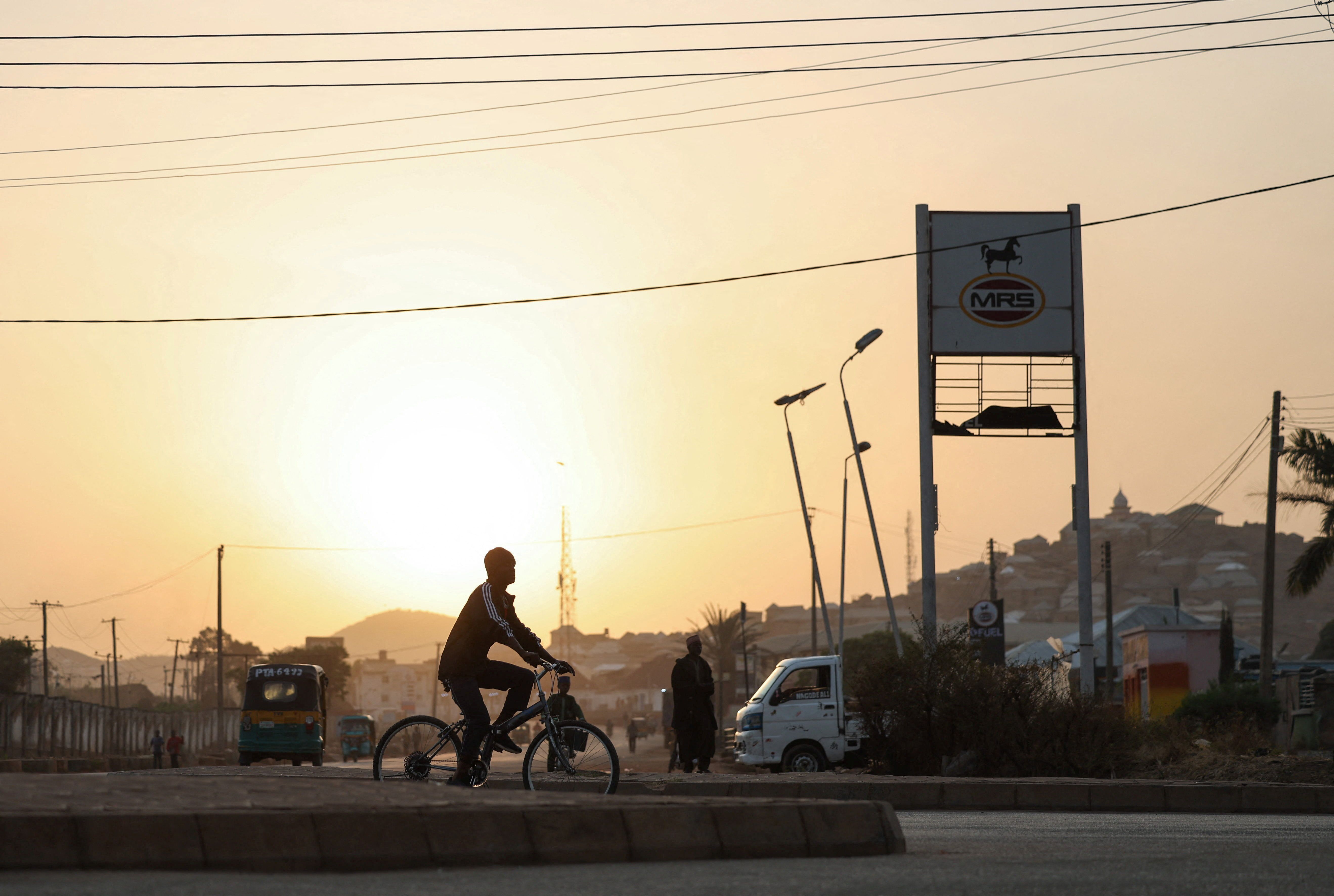 A person rides a bicycle at sunrise in Jos, Plateau State, north central Nigeria.