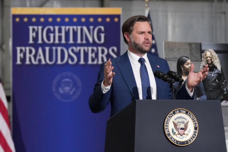 JD Vance and a sign that says FIGHTING FRAUDSTERS