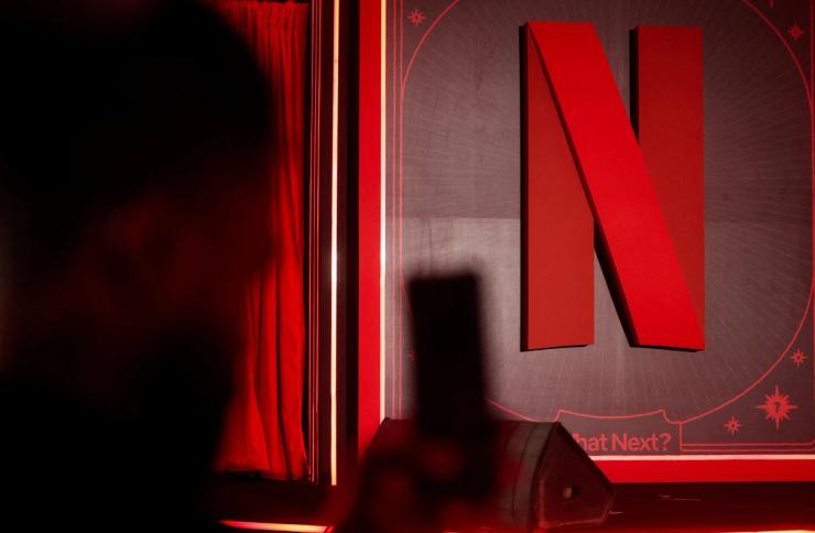 A man takes a photograph next to a Netflix logo during an event in Mumbai, India.