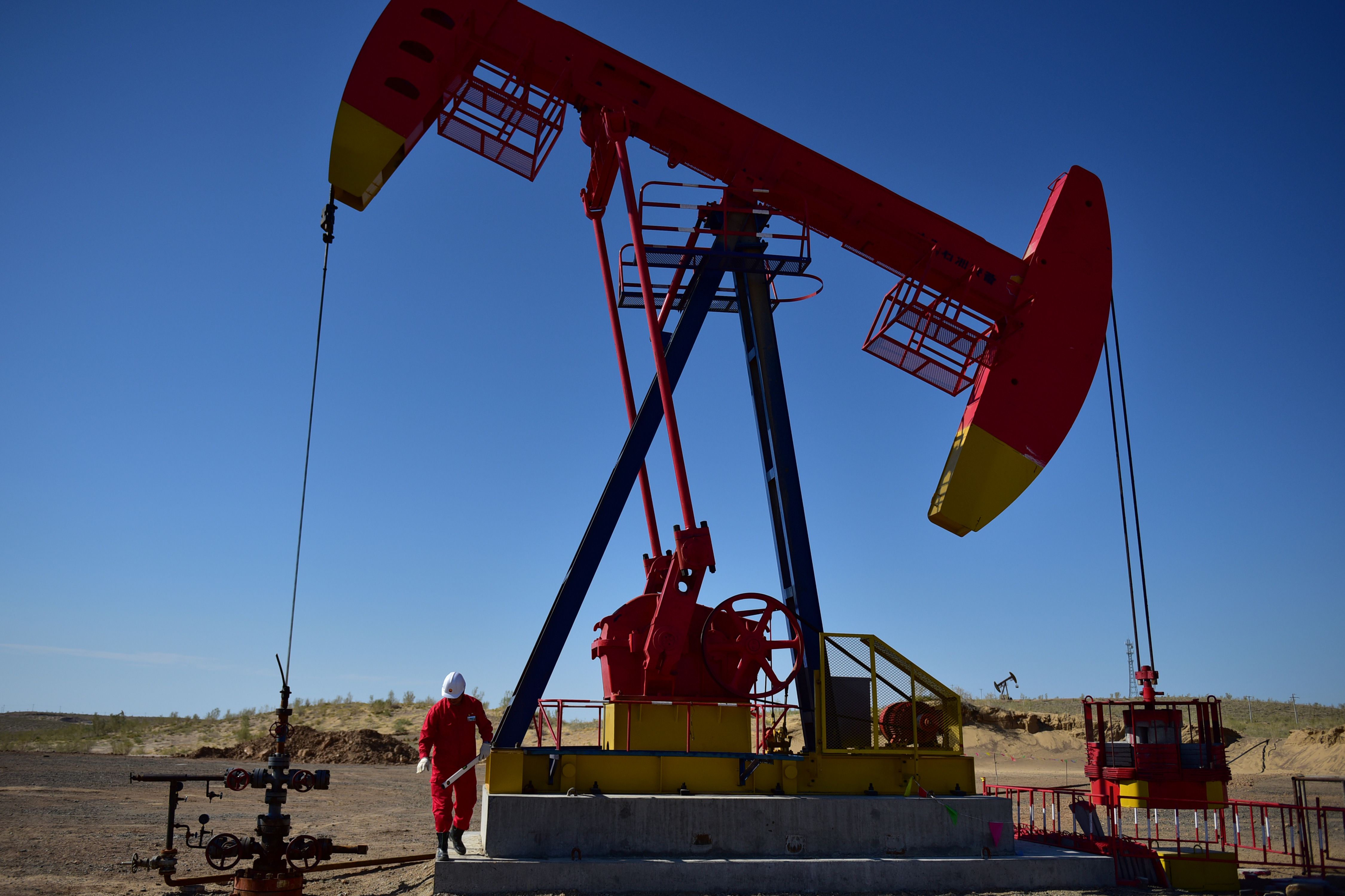 A PetroChina worker inspects a pump jack in Xinjiang Uighur Autonomous Region, China 