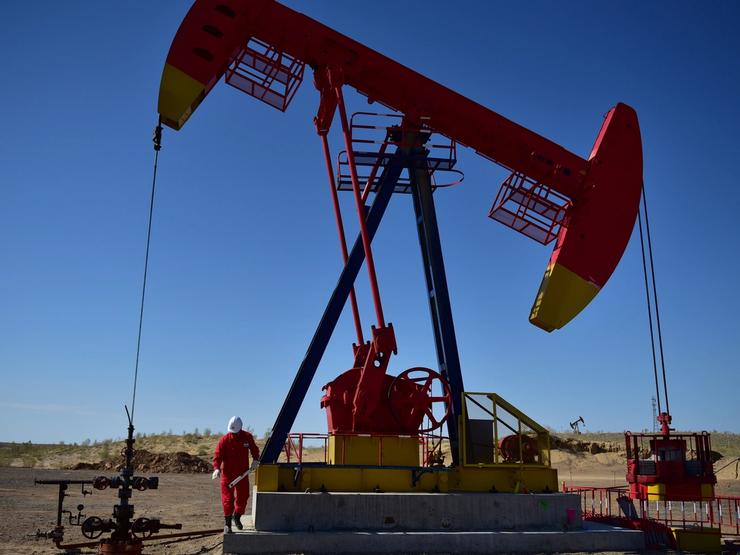 A PetroChina worker inspects a pump jack in Xinjiang Uighur Autonomous Region, China