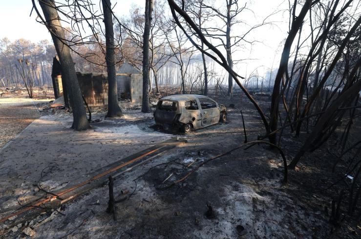 A burnt car sits in an area affected by a wildfire, in Le Porge, Gironde.