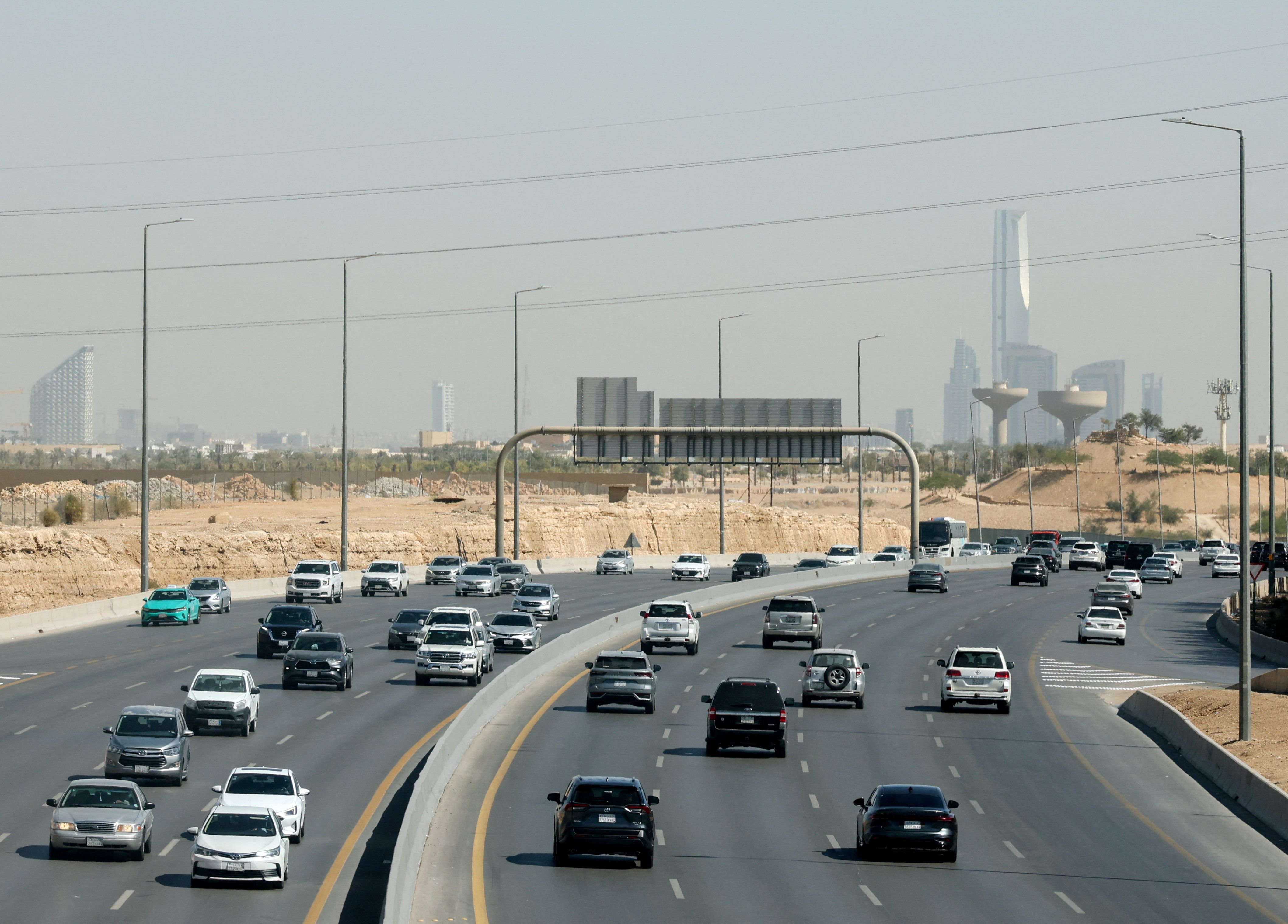 Traffic moves on a road, with the city’s skyline visible in the background, in Riyadh.