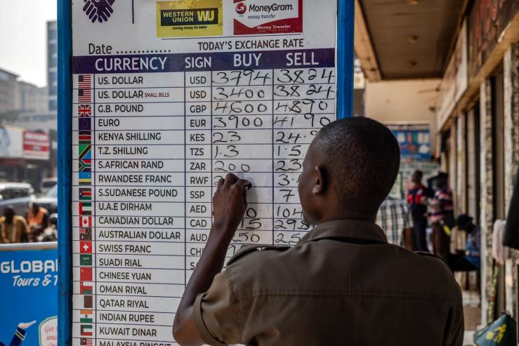 A man working for a forex bureau changes the value on an exchange rate board in downtown Kampala, Uganda.