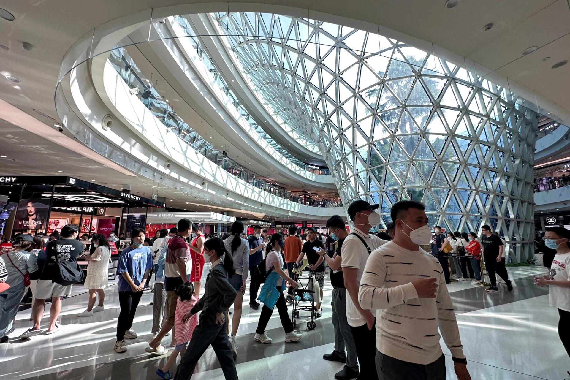 People wearing face masks following the coronavirus disease (COVID-19) outbreak walk in the Sanya International Duty-Free shopping complex in Sanya, Hainan province, China.