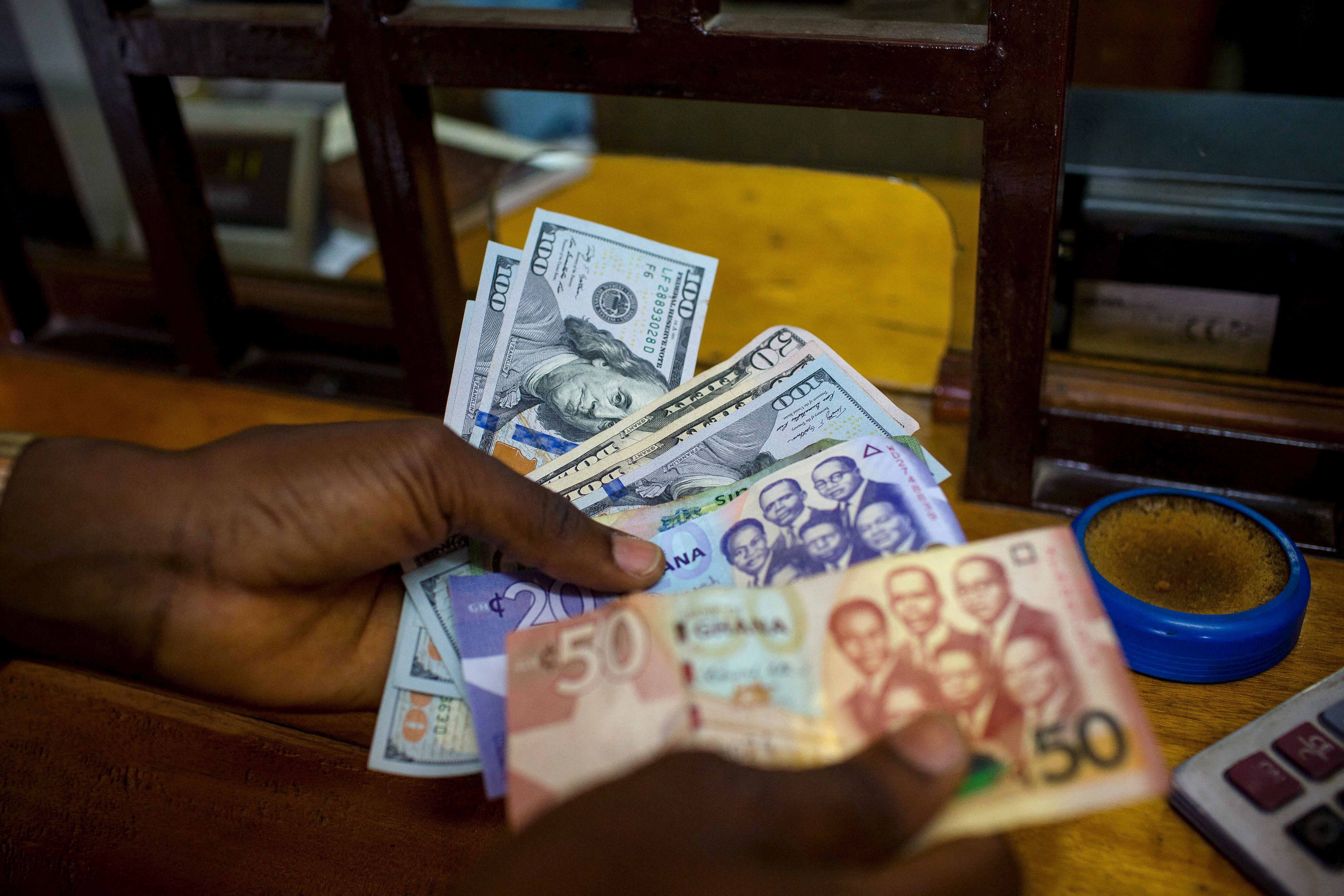 A man trades US dollars for Ghanaian cedis at a currency exchange office in Accra, Ghana.