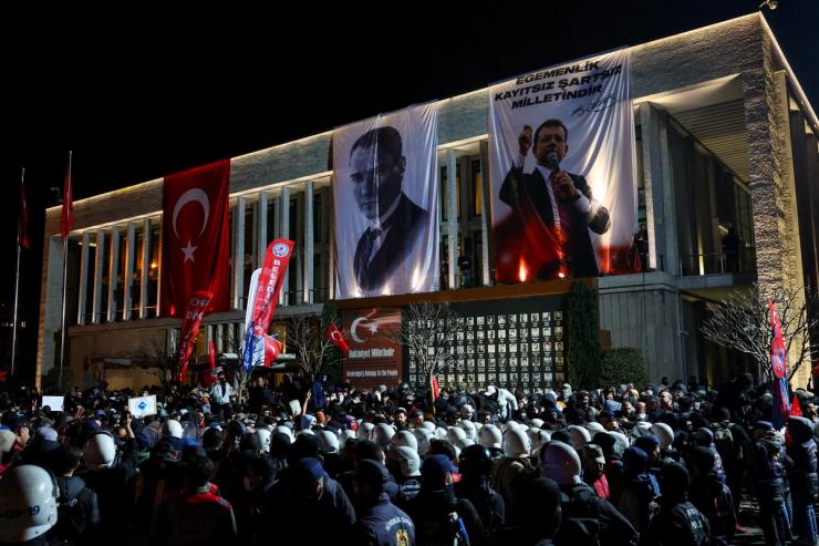 Police officers stand guard, as people take part in a protest against the arrest of Istanbul Mayor Ekrem Imamoglu as part of a corruption investigation.