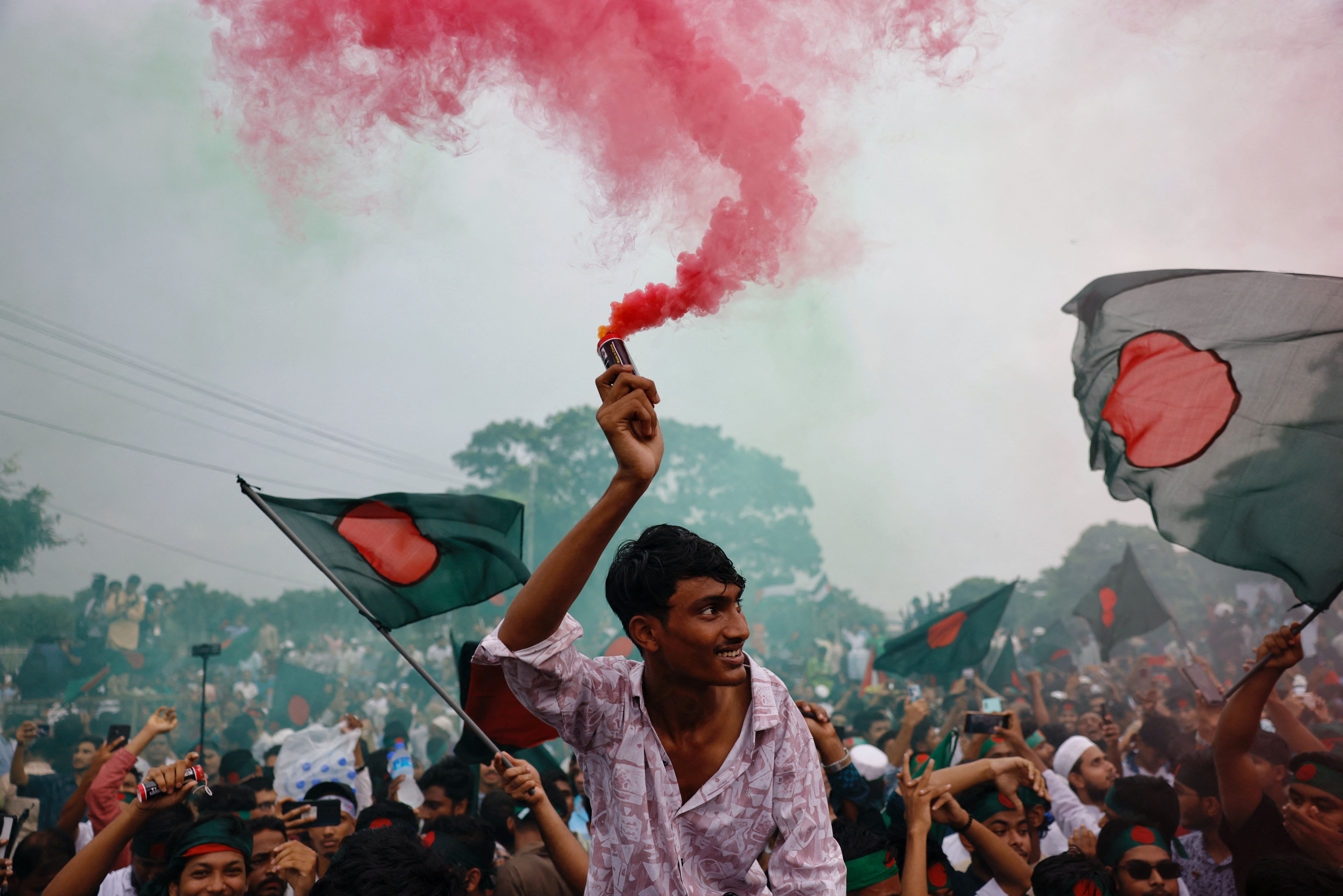 People use coloured smoke and wave flags as they celebrate the one year anniversary since student-led protests ousted Bangladesh’s former Prime Minister Sheikh Hasina.