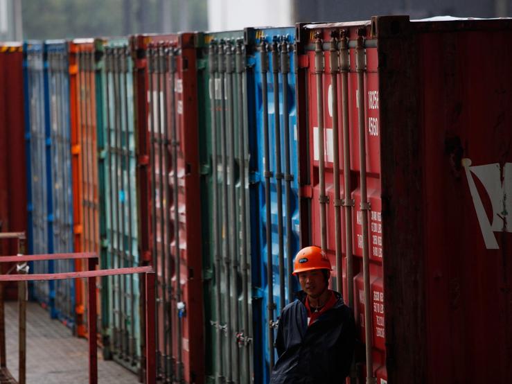 A worker stands next to a shipping container area in Shanghai Yangshan port
