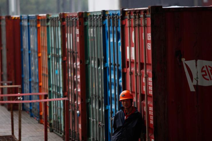 A worker stands next to a shipping container area in Shanghai Yangshan port