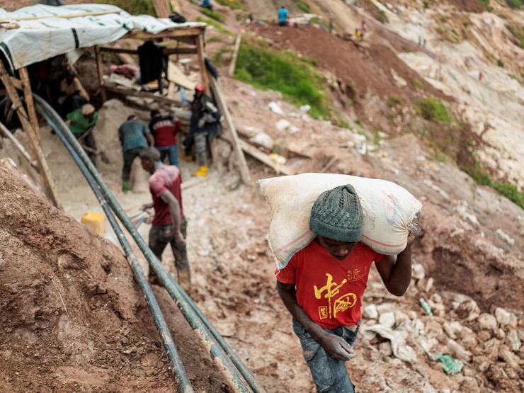 A laborer carries a sack of ore at the Rubaya coltan mine.