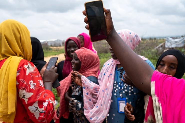 Women consulting their smartphones at a community cooking event in Chad on 30 Aug. 2024.