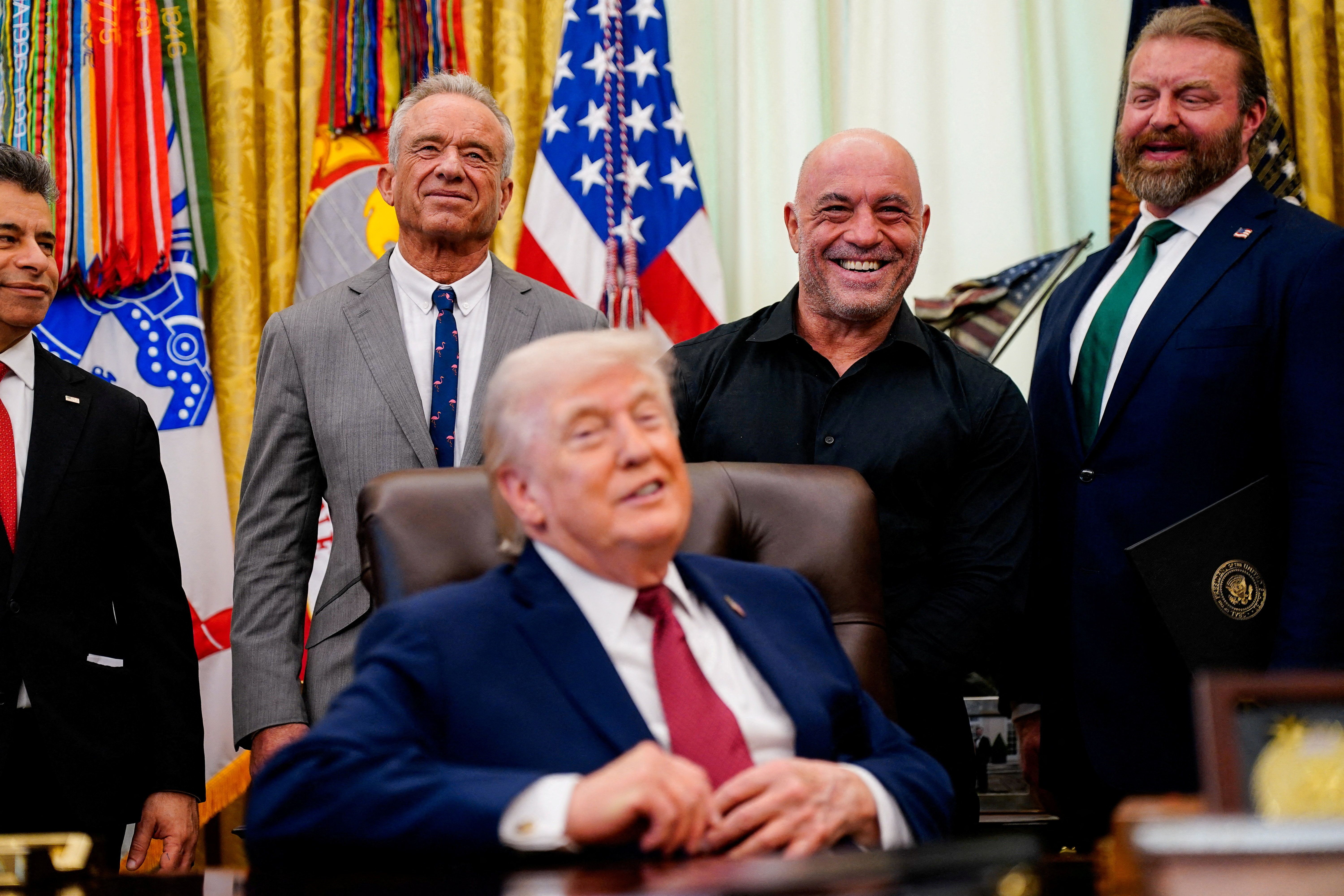  Podcaster Joe Rogan and HHS Secretary Robert F. Kennedy Jr. stand behind President Donald Trump.