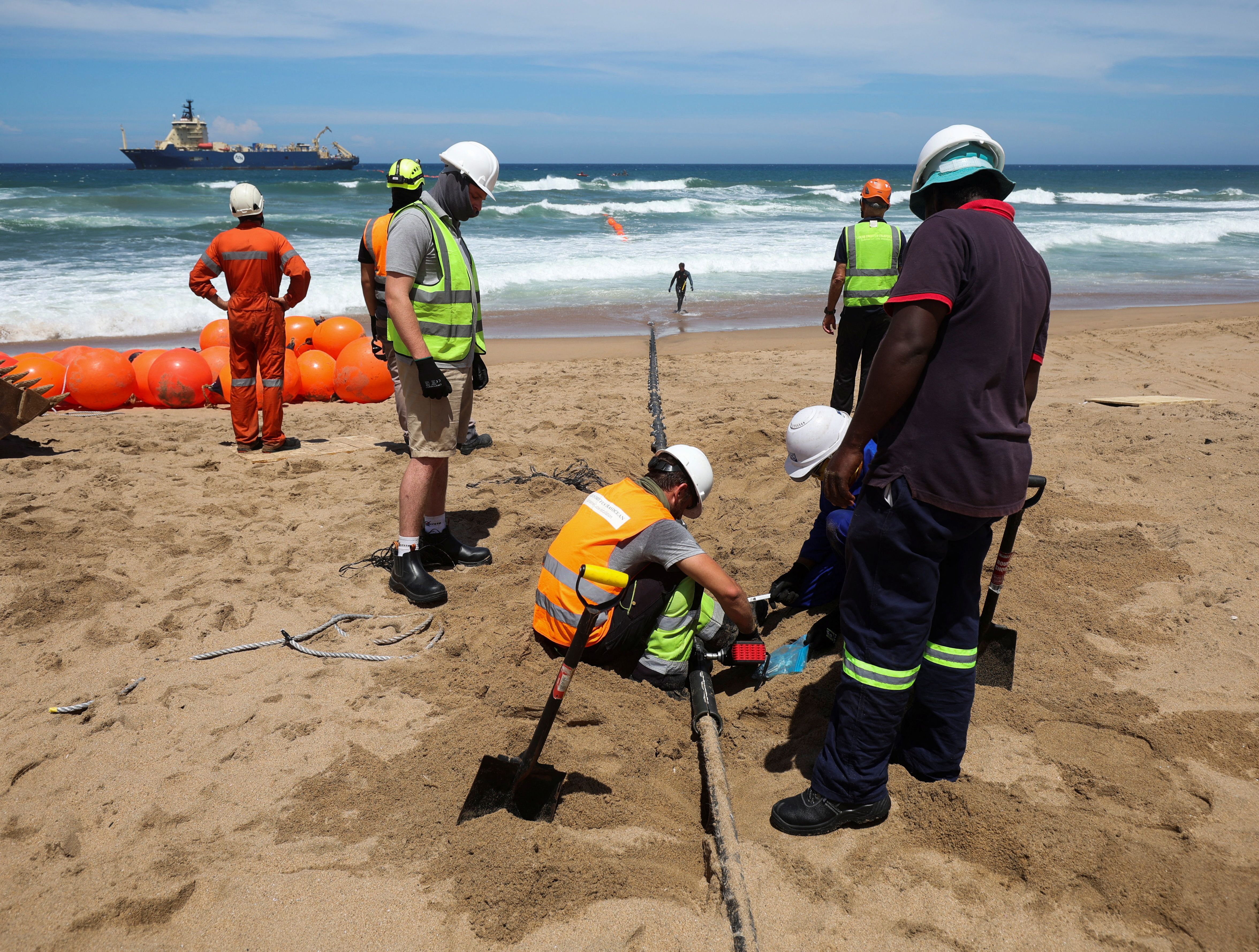 Workers install the 2Africa undersea cable on the beach in Amanzimtoti, South Africa