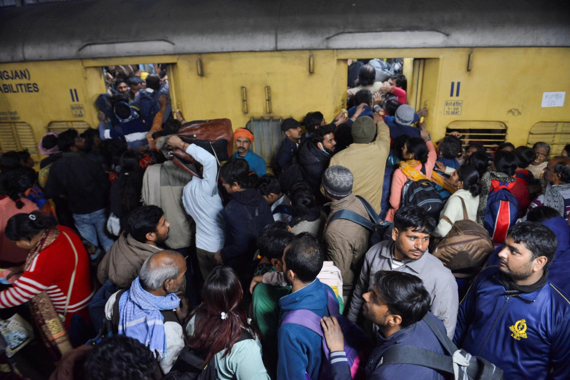 People, including Hindu pilgrims on their way to attend the “Maha Kumbh Mela”, or the Great Pitcher Festival, jostle to board a train at the New Delhi Railway Station.