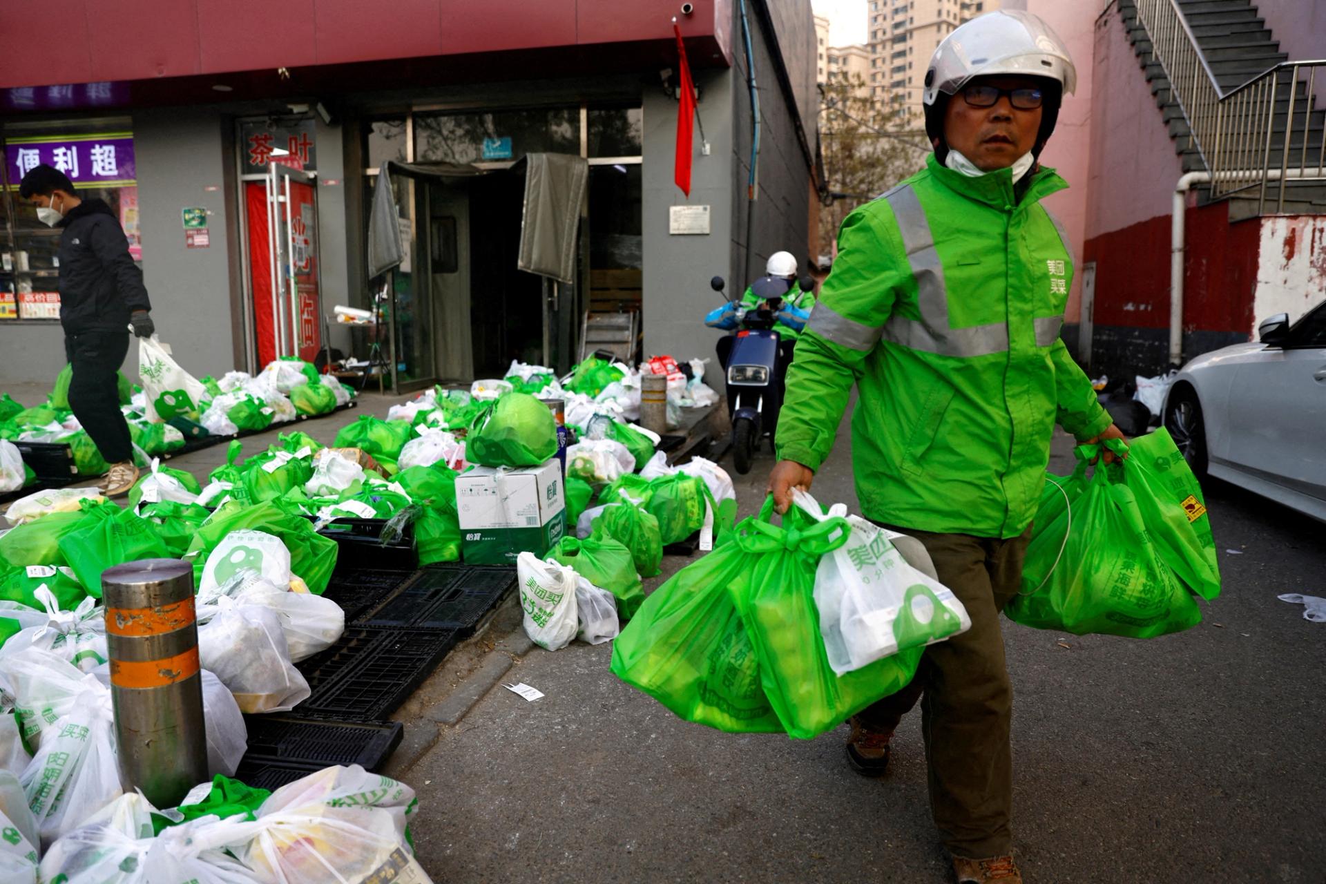 A delivery worker picks up goods at a logistics station of an online grocery platform in Beijing, China.