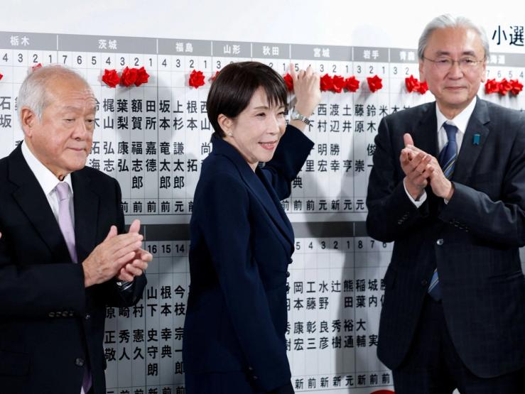 Japan’s Prime Minister Sanae Takaichi, leader of the ruling Liberal Democratic Party (LDP), next to LDP Secretary-General Shunichi Suzuki and LDP Election Strategy Chief Keiji Furuya, places a red paper rose on the name of an elected candidate at the LDP headquarters on general election day in Tokyo