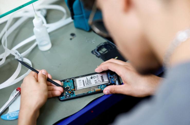 A smartphone repair technician works on a phone.