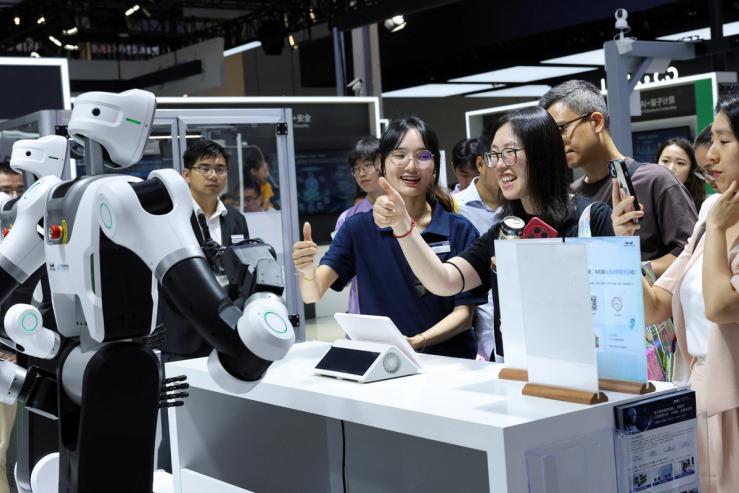 People interact with a humanoid robot at a Mech-Mind booth during the World Artificial Intelligence Conference in Shanghai