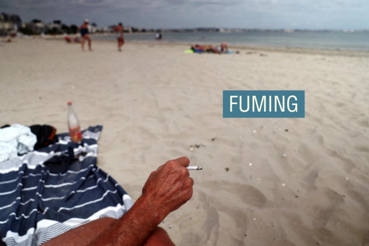 A beachgoer holds a cigarette