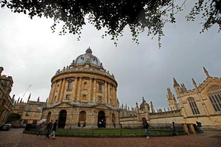 People walk in front of the buildings of Oxford University.