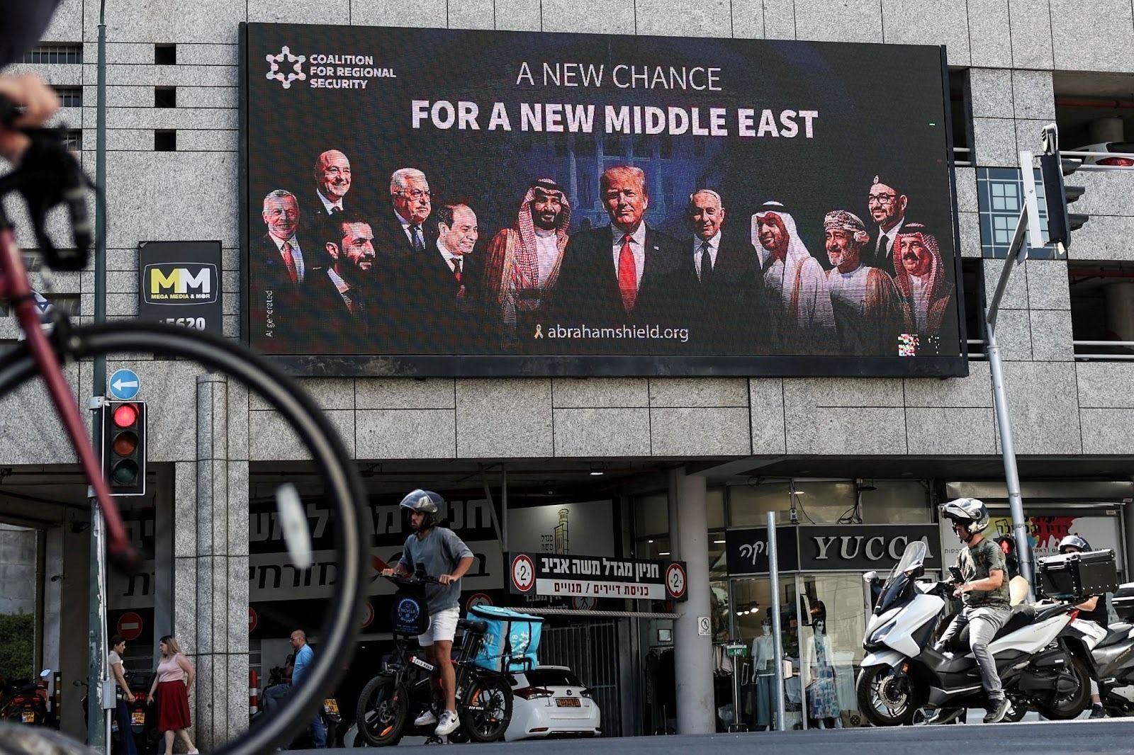 People walk by a billboard sponsored by the Coalition for Regional Security calling for the expansion of the Abraham Accords, in Israel’s Ramat Gan