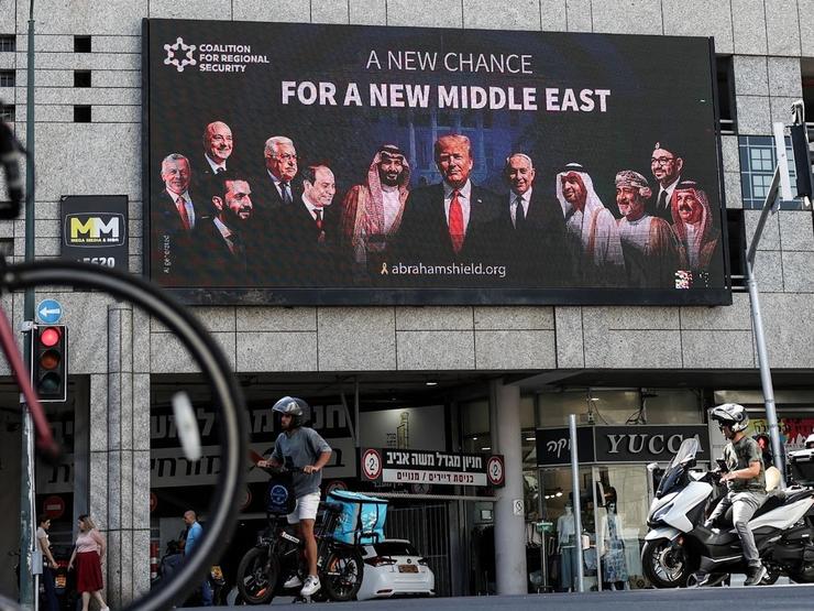 People walk by a billboard sponsored by the Coalition for Regional Security calling for the expansion of the Abraham Accords, in Israel’s Ramat Gan