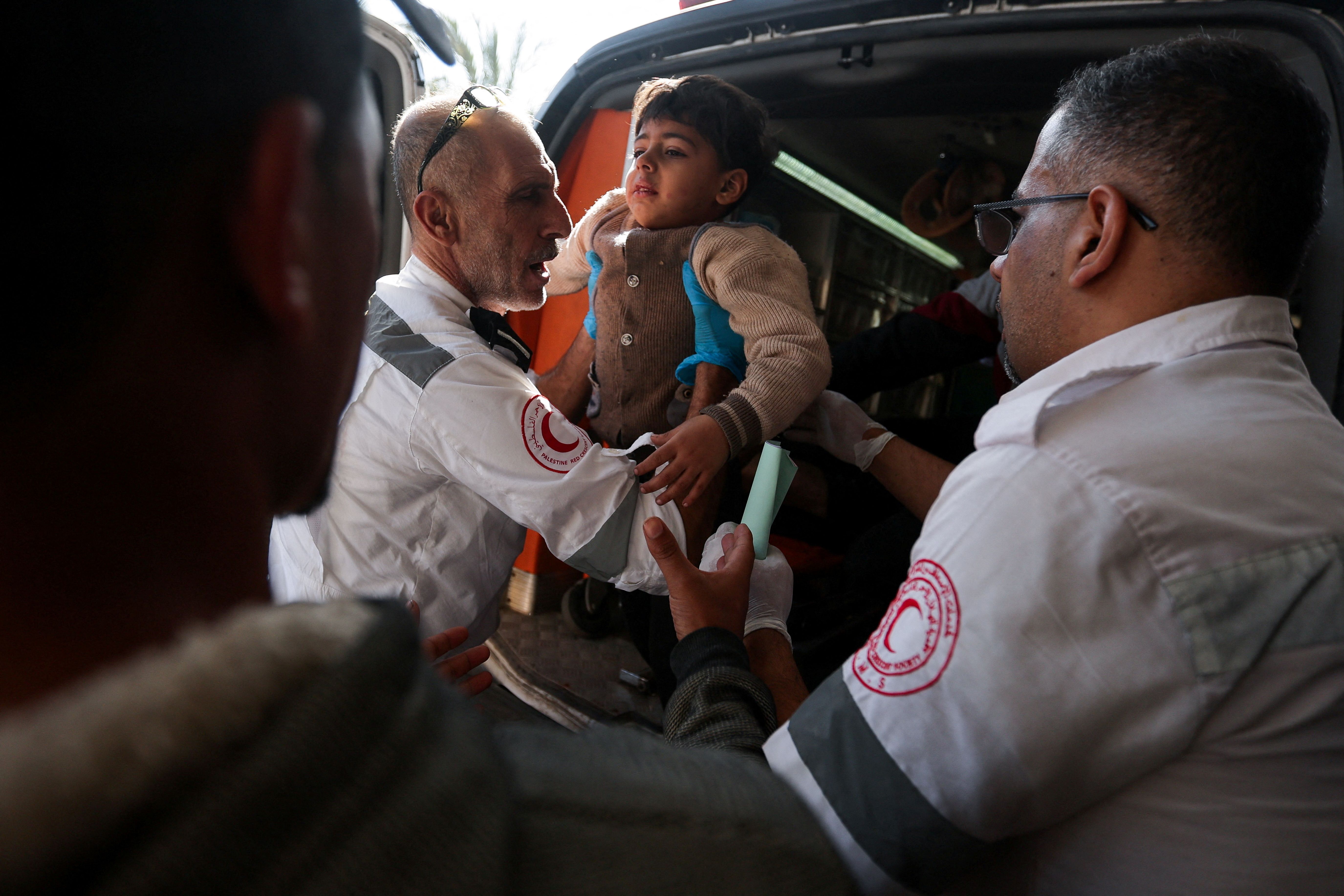 Members of ‘Palestine Red Crescent Society’ assist a Palestinian child as wounded Palestinians are rushed into Nasser hospital following Israeli strikes, amid the ongoing conflict between Israel and the Palestinian Islamist group Hamas, in Khan Younis, in the southern Gaza Strip, December 4, 2023. REUTERS/Ibraheem Abu Mustafa