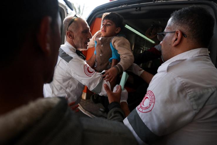 Members of ‘Palestine Red Crescent Society’ assist a Palestinian child as wounded Palestinians are rushed into Nasser hospital following Israeli strikes, amid the ongoing conflict between Israel and the Palestinian Islamist group Hamas, in Khan Younis, in the southern Gaza Strip, December 4, 2023. REUTERS/Ibraheem Abu Mustafa