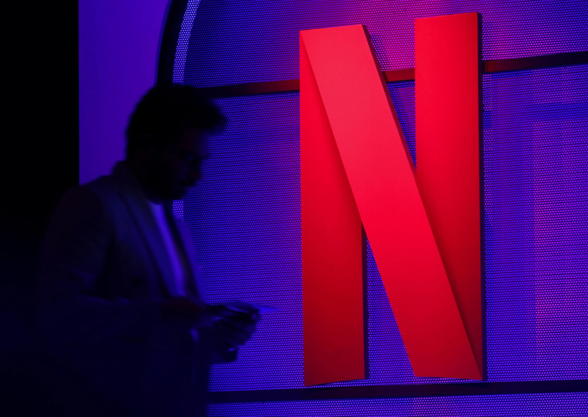 A man stands next to a logo of Netflix during an event in Mumbai, India.